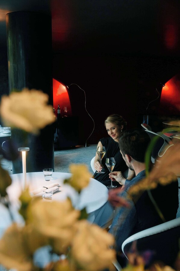 A dimly lit restaurant with a round table, candles, and a glass of wine.