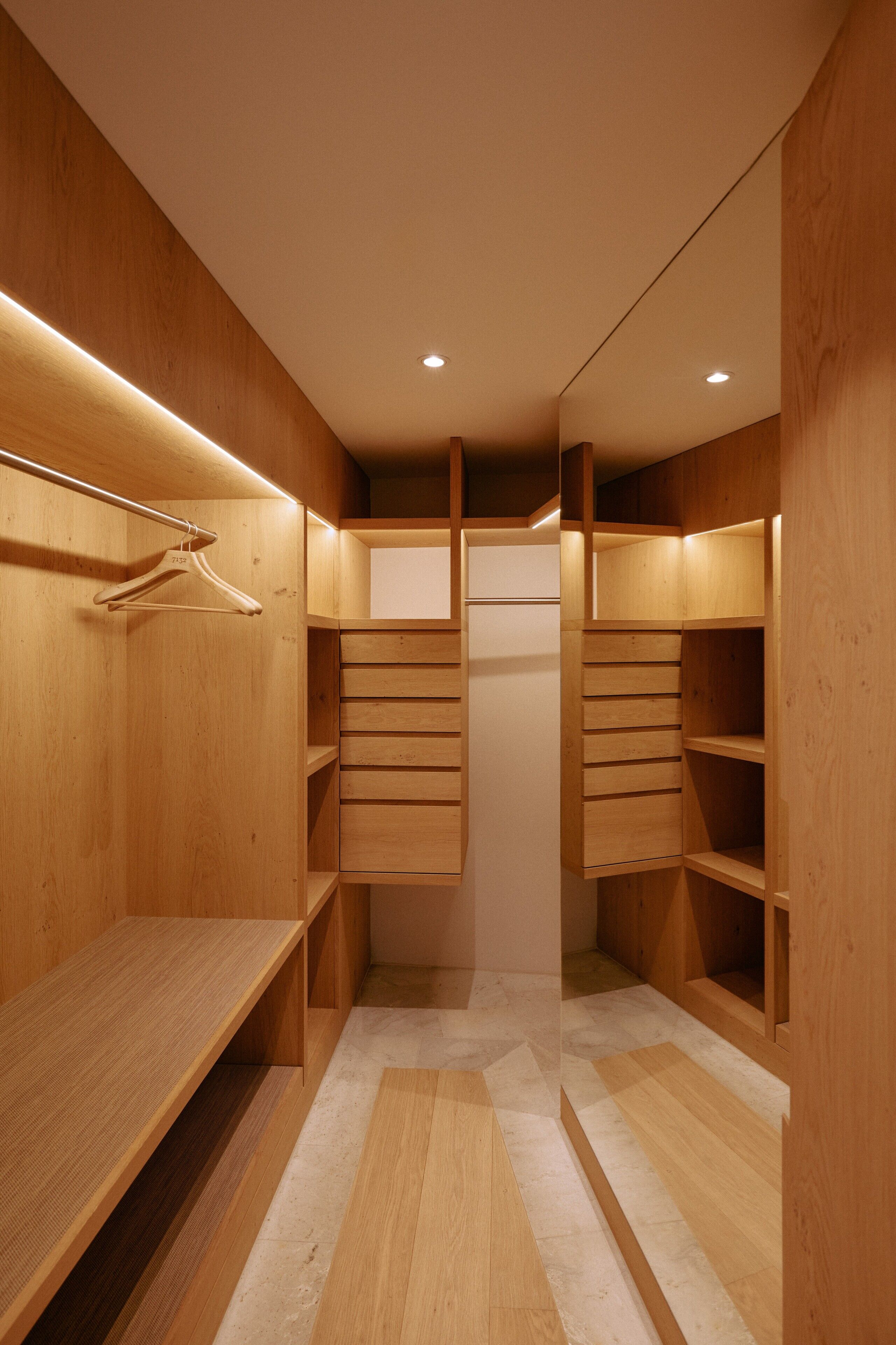 Ein begehbarer Kleiderschrank aus Holz mit eingebauten Regalen und einer Kleiderstange.