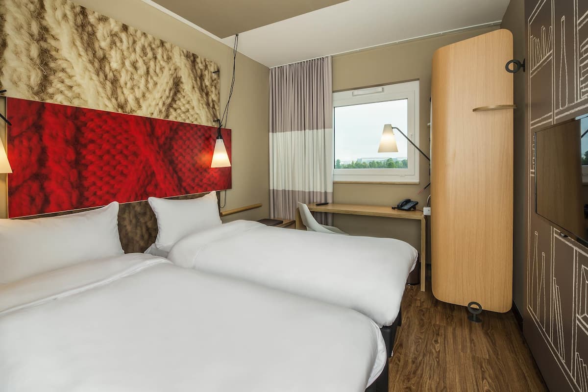 Hotellihuone, jossa on sänky, työpöytä, tuoli, vaatekaappi ja ikkuna, josta on näkymä.