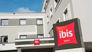 En moderne hotelbygning med et tydeligt ibis logo og et skilt, der angiver, at det ligger i München.