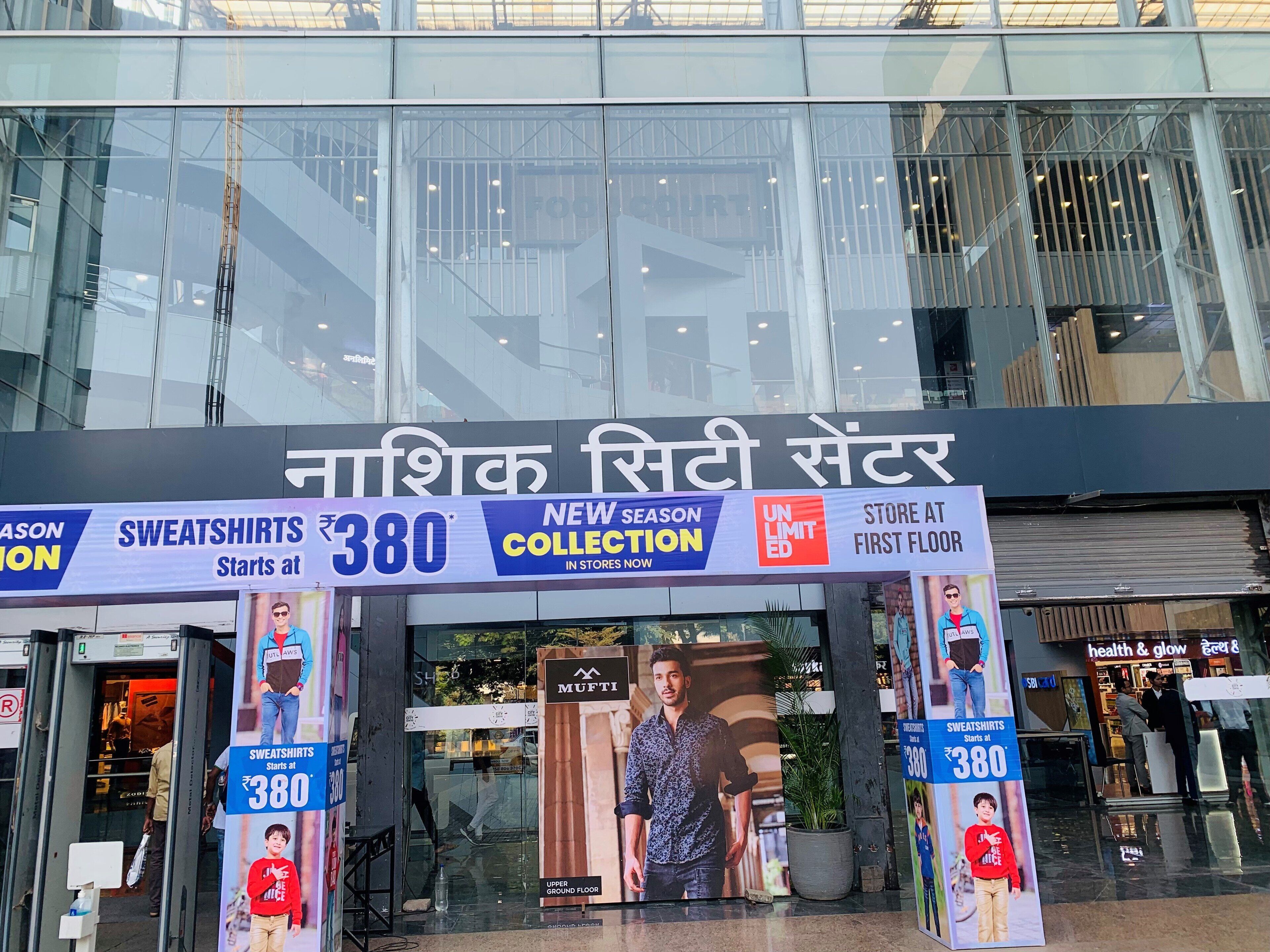 A shopping mall entrance with a sign advertising a new season collection of sweatshirts starting at ₹380.