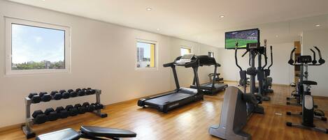 A gym with treadmills, elliptical machines, and dumbbells.