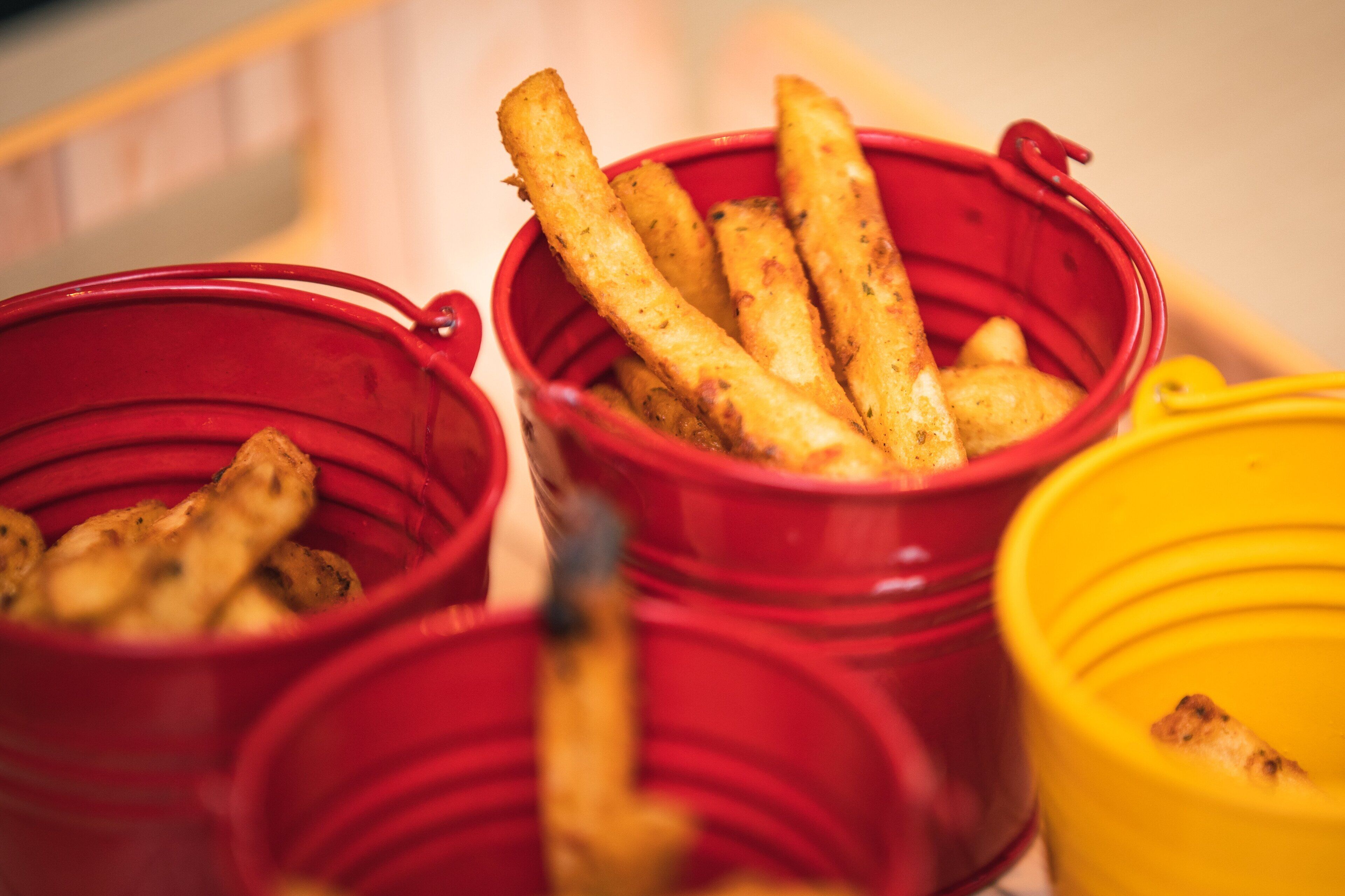 Three red containers with food items, likely a buffet setting.