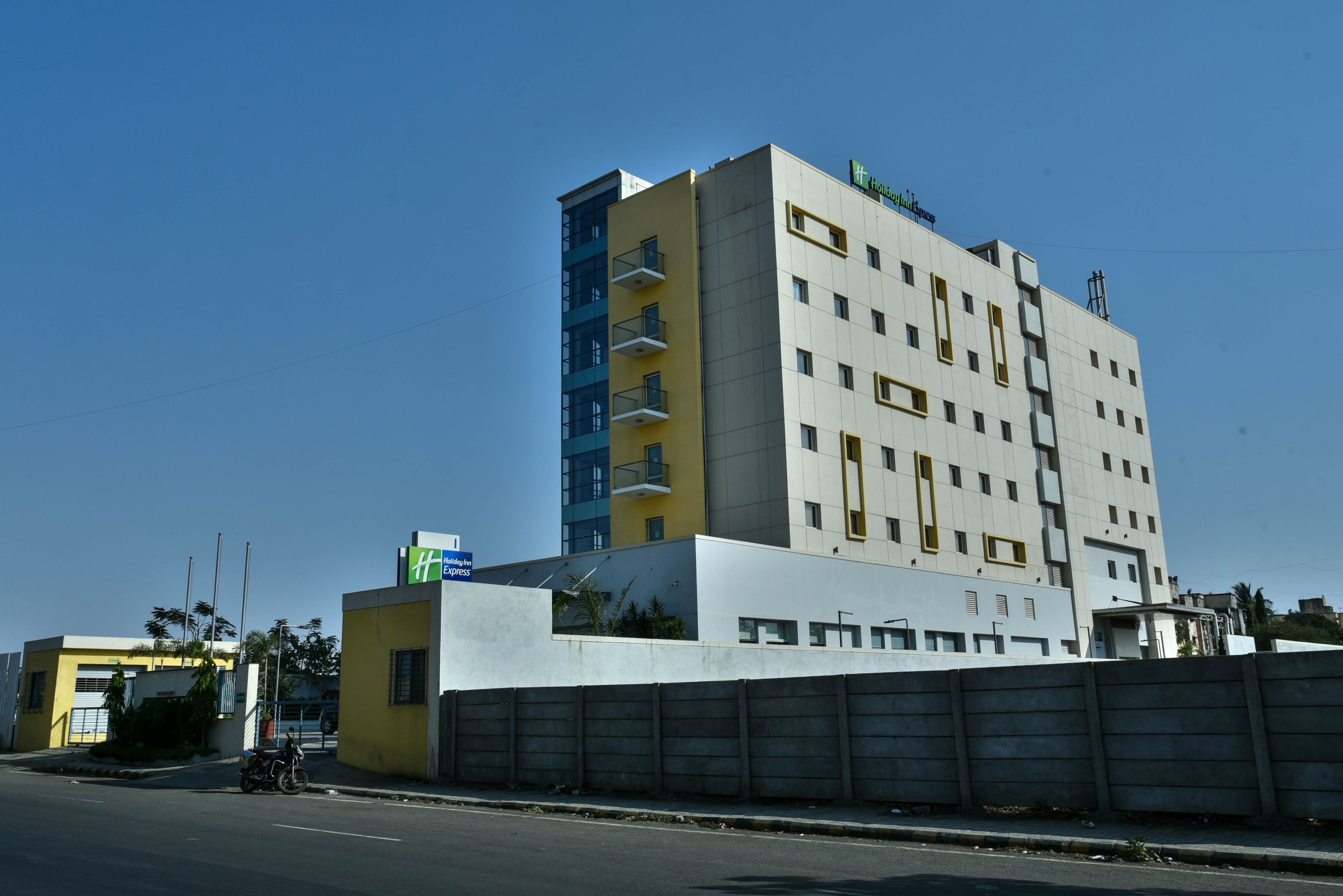 A multi-story hotel with a yellow and white facade, several balconies, and a sign indicating it is a Holiday Inn Express.