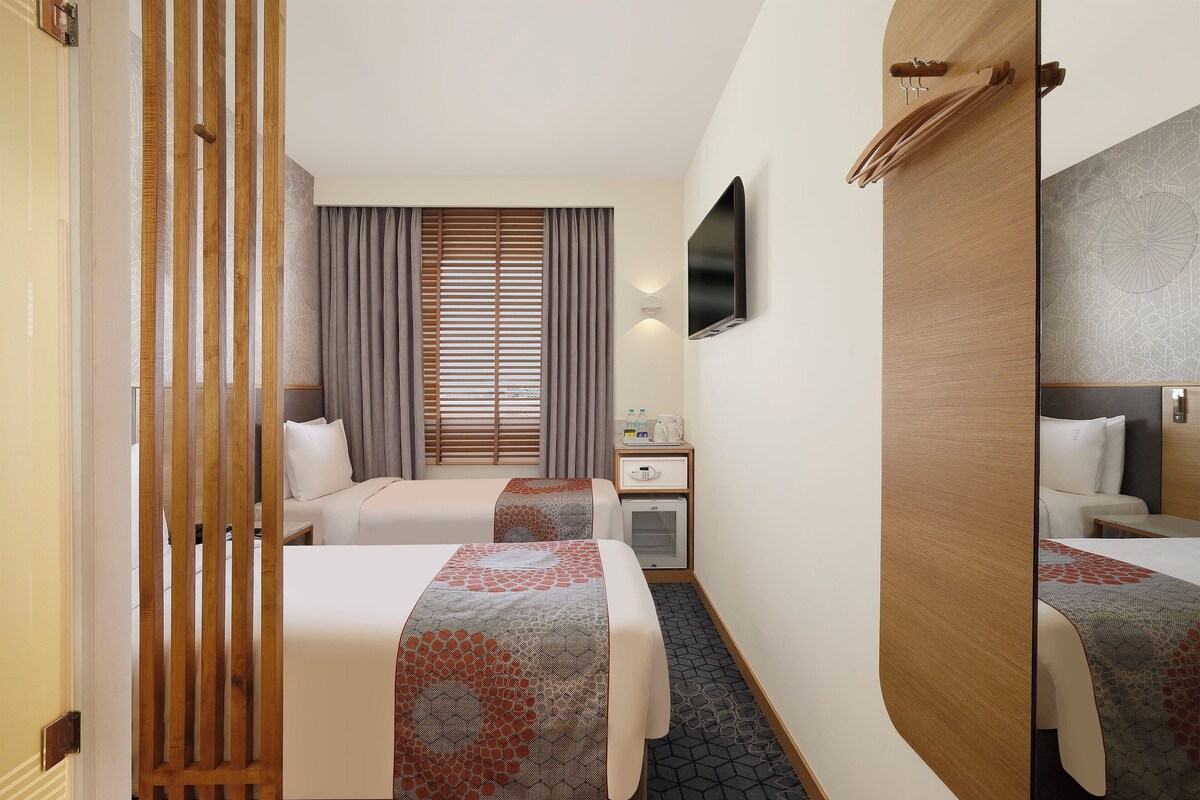Une chambre d’hôtel avec deux lits, un bureau, une télévision et une armoire.