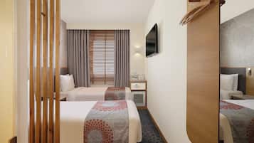 Une chambre d’hôtel avec deux lits, un bureau, une télévision et un minibar.
