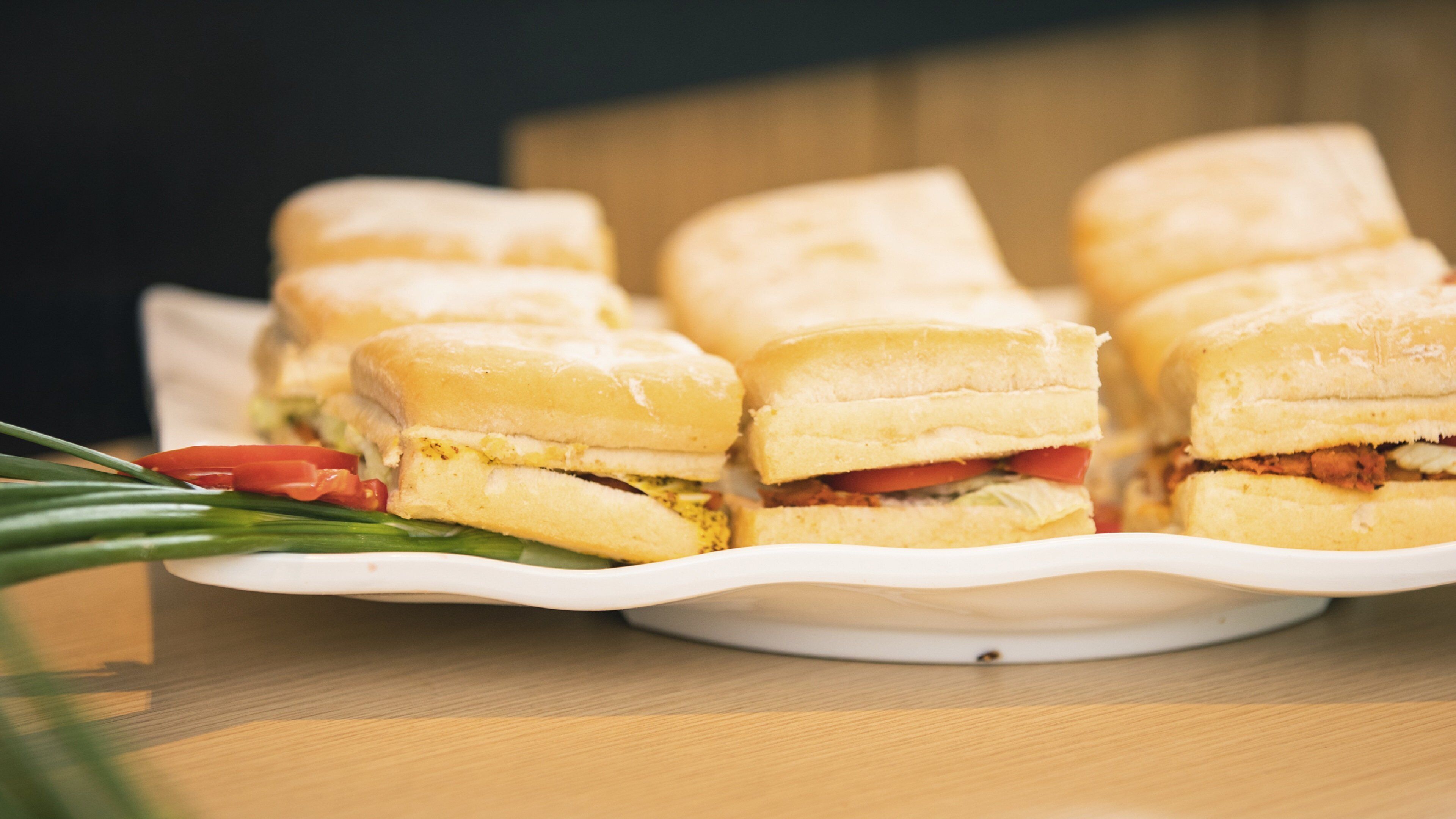 Ein Tablett mit Sandwiches, bei denen die Füllung aus Salat und Tomaten erkennbar ist.