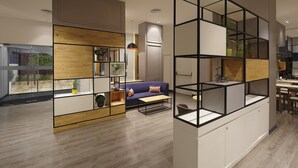 Un salon moderne avec un canapé bleu, des étagères en bois et un coin repas comprenant une table et des chaises.