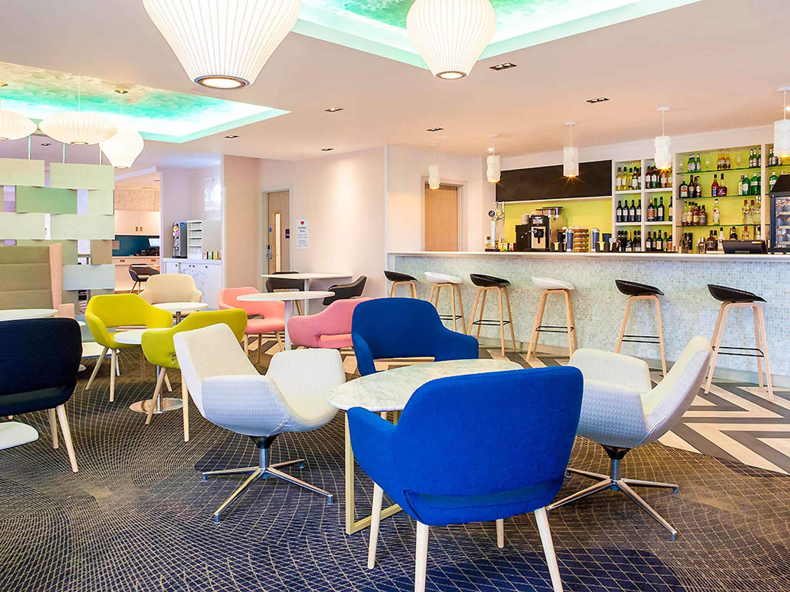 A modern bar area with stools, a counter, and a variety of bottles.