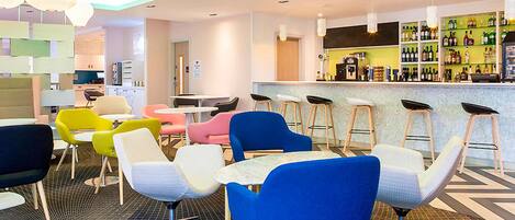 A modern bar area with stools, a counter, and a variety of bottles.