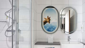 Un baño con ducha, lavamanos y dos espejos.