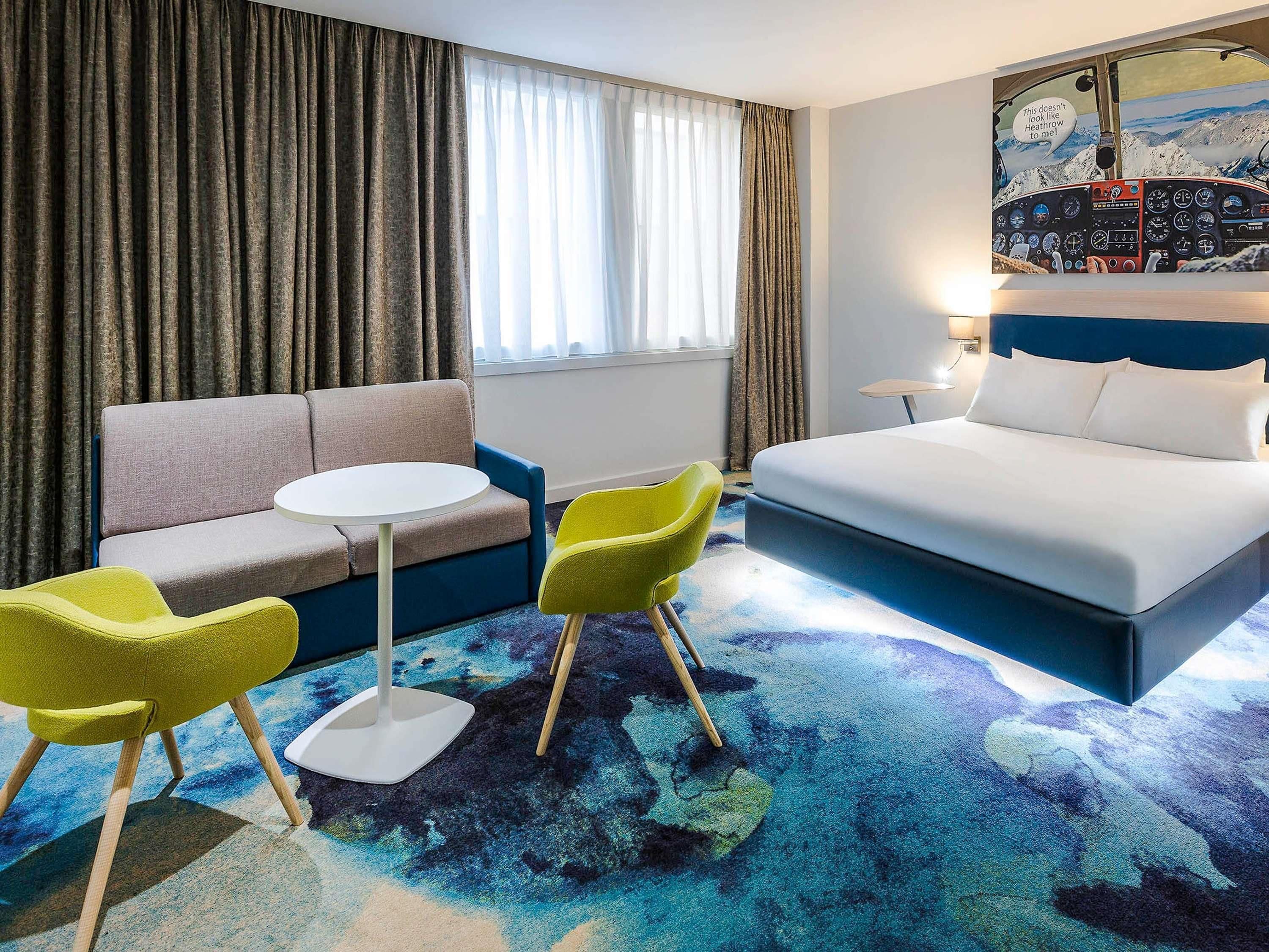 A hotel room with a bed, a sofa, a round table, and two chairs.