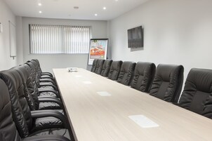 A conference room with a long table and black leather chairs.