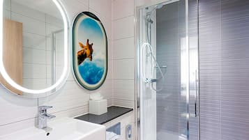 Un baño moderno con un lavabo blanco, un espejo con una imagen de jirafa y una cabina de ducha de vidrio.