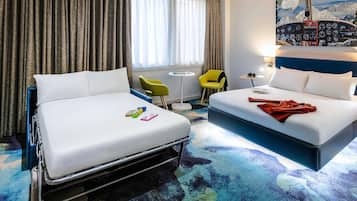 A hotel room with two beds, a desk, a chair, a small table, and a window with curtains.