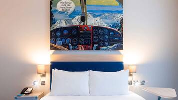 Relax in a stylish room with a unique airplane cockpit painting, a comfortable bed, and convenient bedside lamps.