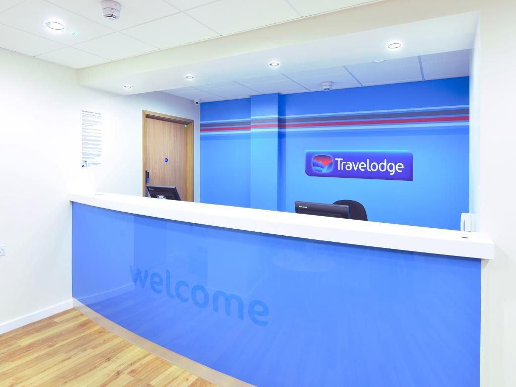 A reception area with a blue wall and a 'Travelodge' logo.