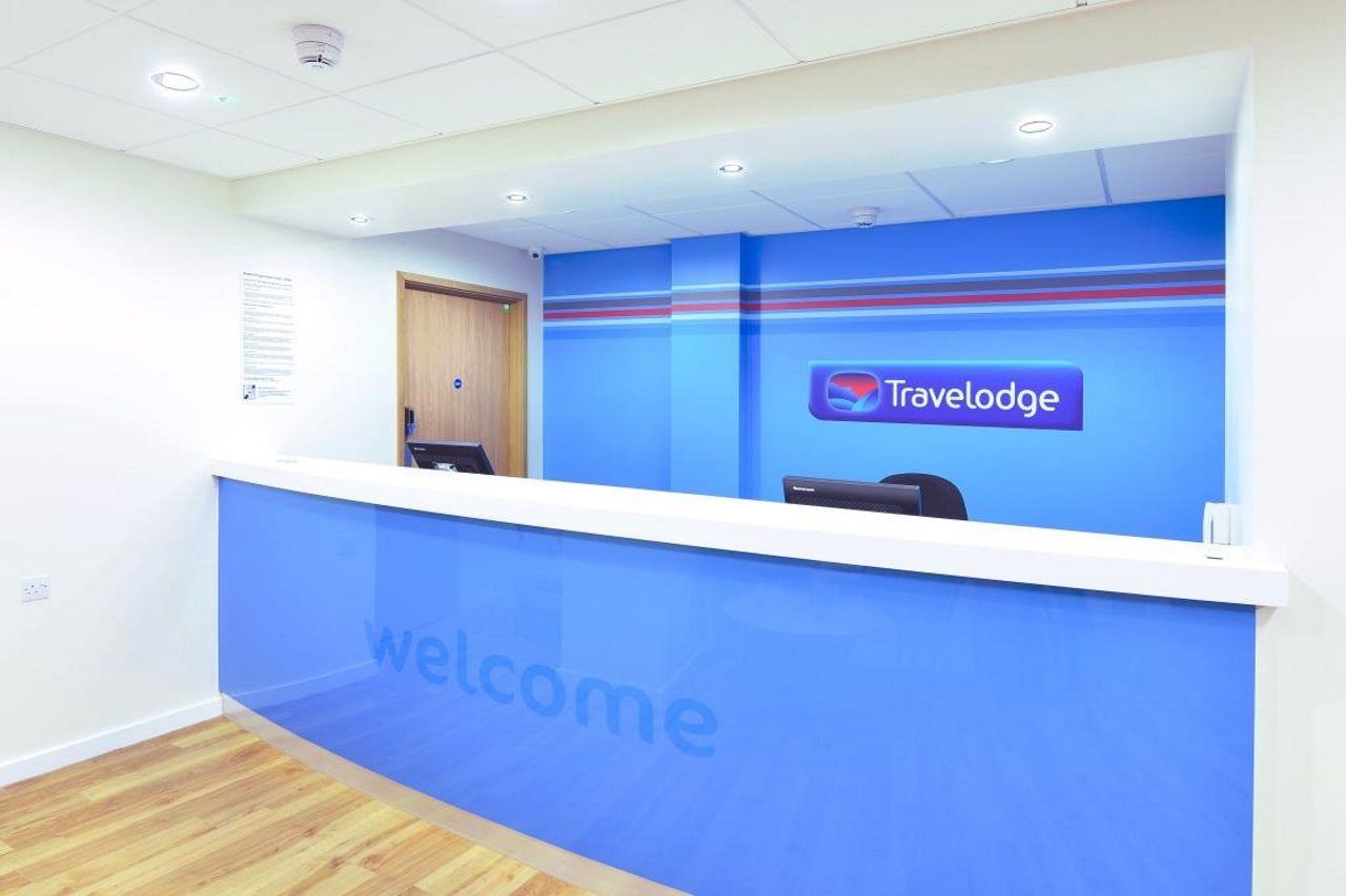 A reception desk with a 'Travelodge' logo and a 'welcome' sign.