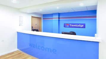 A reception desk with a 'Travelodge' logo and a 'welcome' sign.