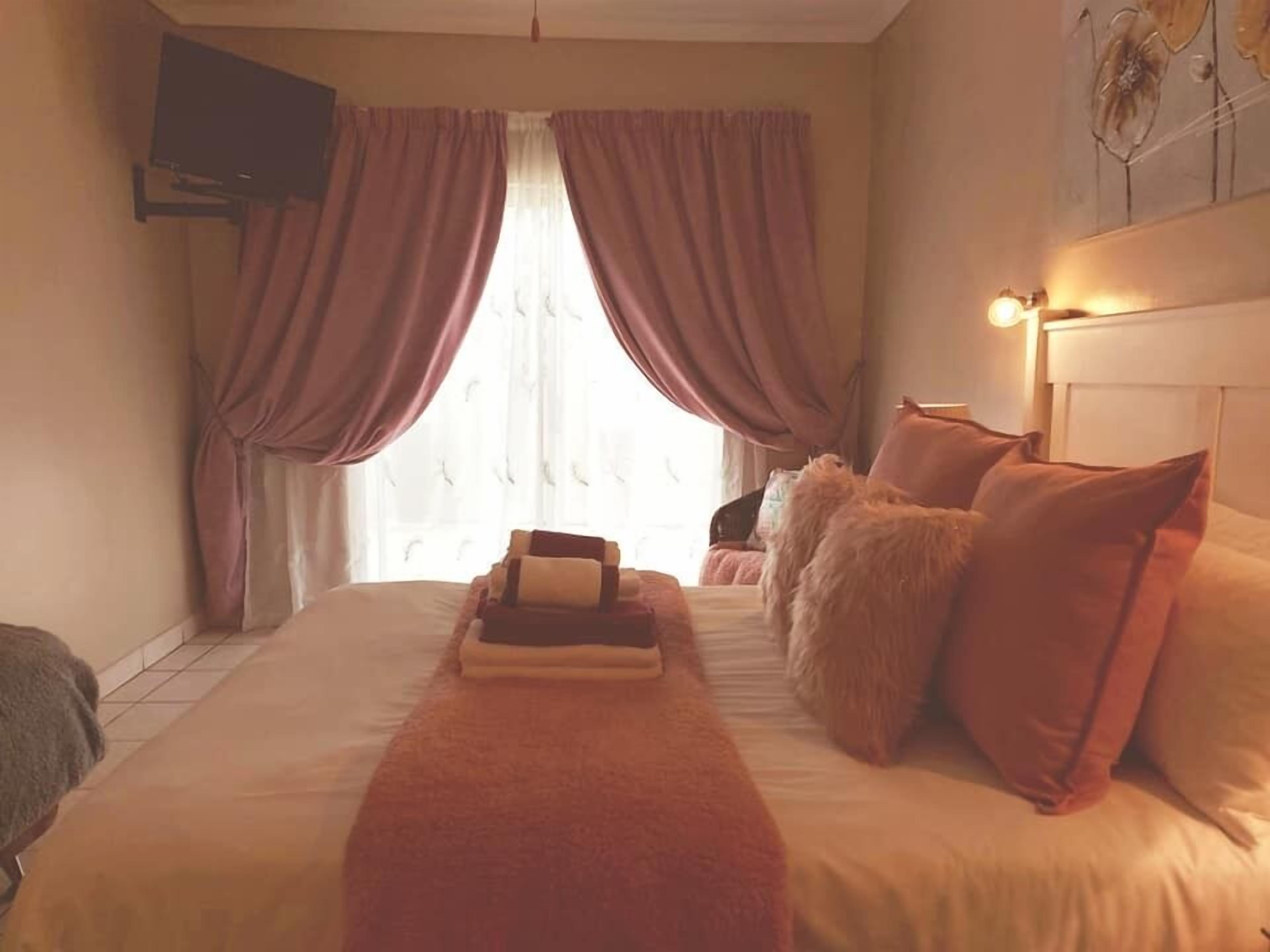Habitación de hotel con una cama grande, un televisor en la pared y una ventana con cortinas.