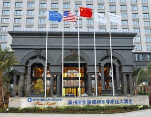 The Wyndham Grand Plaza Royalty building with multiple flags, including the American and Chinese flags, and a sign indicating its name in both English and Chinese. - Wyndham Grand Plaza Royale Mingfa Zhangzhou (Zhangzhou)