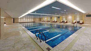 An indoor swimming pool with multiple lanes, lounge chairs, and a modern ceiling design. - Wyndham Grand Plaza Royale Mingfa Zhangzhou (Zhangzhou)