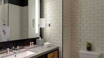 A modern bathroom with two sinks, a large mirror, a toilet, and a small trash bin.