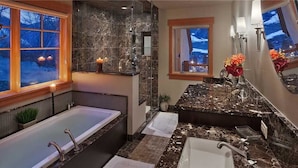 A modern bathroom with a large bathtub, a separate shower area, and a vanity with a marble countertop. - Storm Peak Chalet At Ski Time (Steamboat Springs)