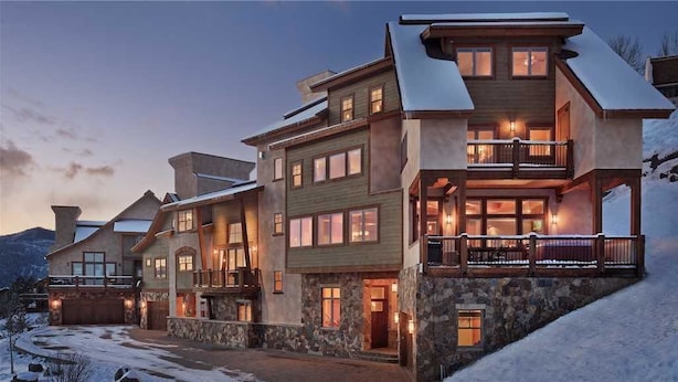A multi-story lodge with a stone facade, multiple balconies, and a snow-covered landscape. - Storm Peak Chalet At Ski Time (Steamboat Springs)