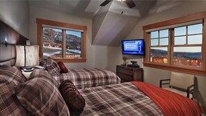 A bedroom with two beds, a television, and large windows with a view of a snowy landscape. - Storm Peak Chalet At Ski Time (Steamboat Springs)