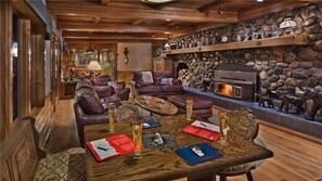 A cozy living room with a stone fireplace, leather sofas, and a wooden coffee table with red and blue placemats. - Senner Chalet At Ski Time (Steamboat Springs)