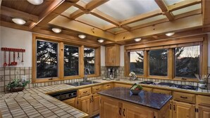 Une cuisine moderne avec des meubles en bois, de grandes fenêtres et un îlot central.