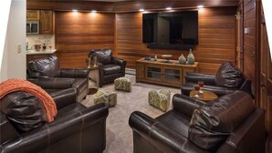 A cozy living room with leather sofas, a coffee table, and a flat-screen TV mounted on the wall. - Trails Edge Lodge (Steamboat Springs)