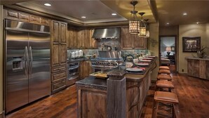 A modern kitchen with stainless steel appliances, wooden cabinets, and a central island with bar stools.