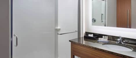 A modern bathroom with a glass shower enclosure, a wooden vanity with a sink, and a mirror above the vanity.