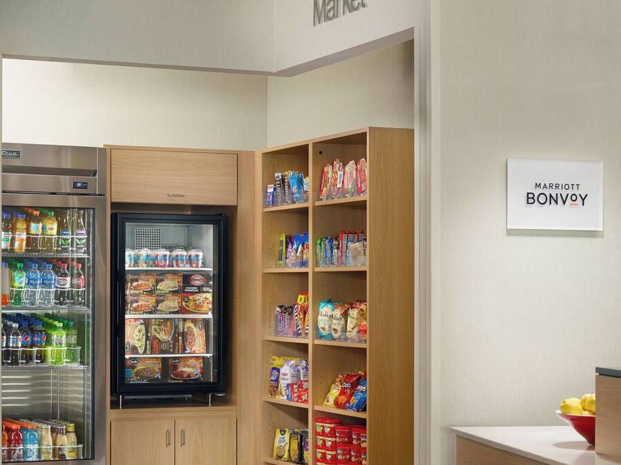 Een kitchenette voorzien van een koelkast, vriezer en planken vol snacks en drankjes.