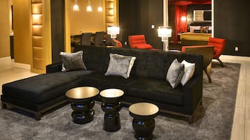 Una sala moderna con un sofá seccional, tres mesas de centro negras y sillas rojas.