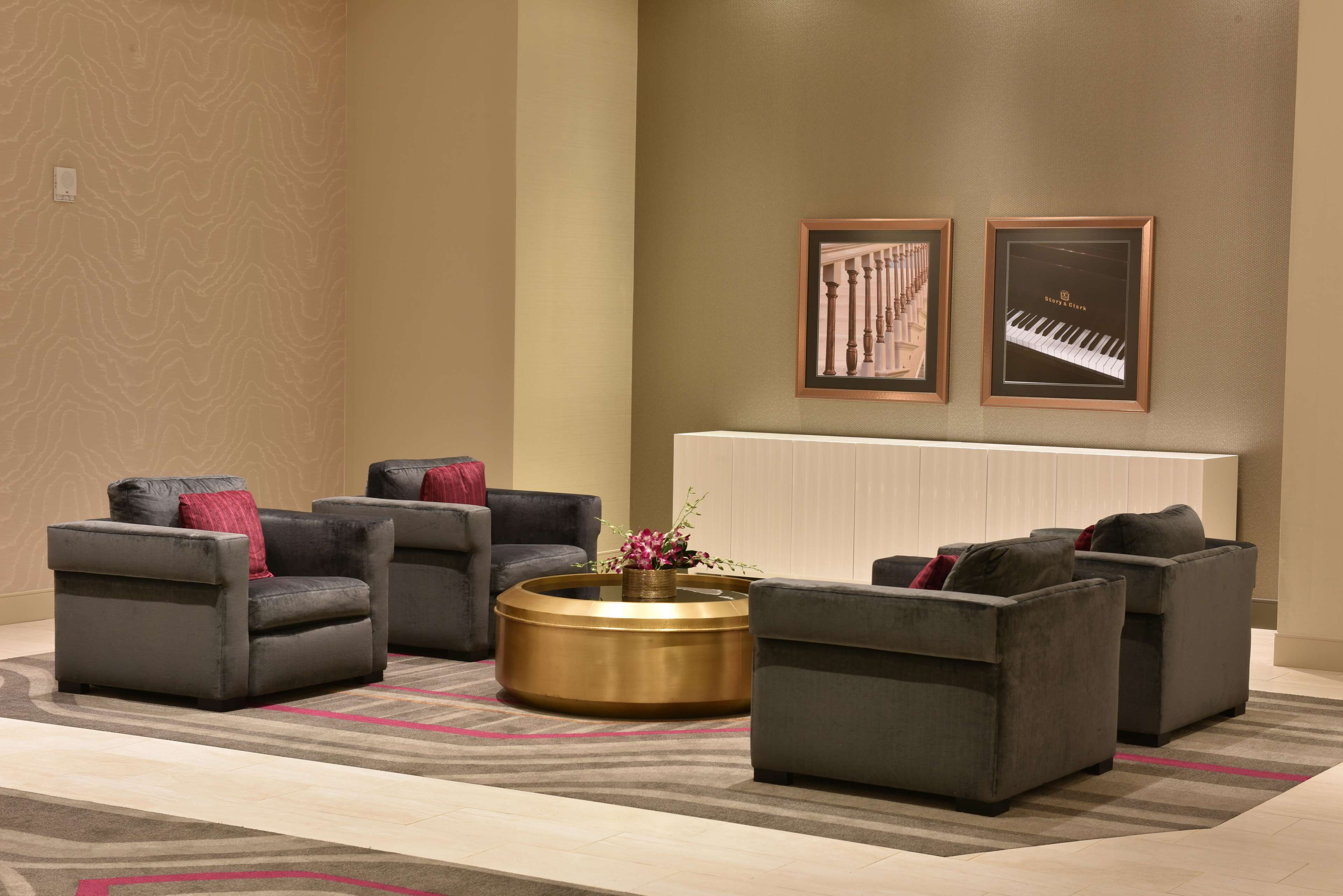 A modern lounge area with grey sofas, a central round coffee table, and two framed artworks on the wall.