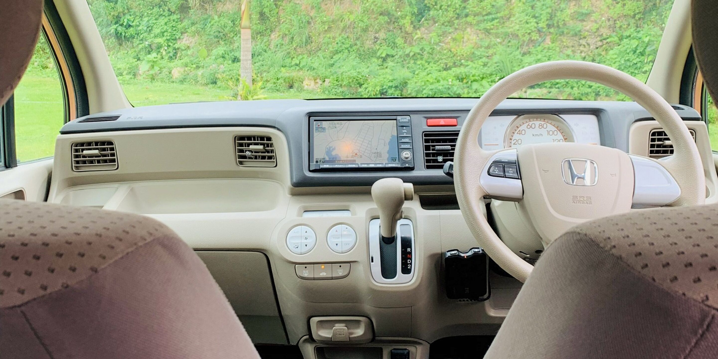 A car's interior with a steering wheel, dashboard, and gear shift.