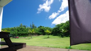 A patio with a view of a grassy area and trees.