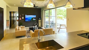 A modern kitchen with a large island, a built-in oven, and a flat-screen TV mounted on the wall.