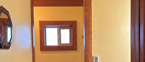 A bathroom with wooden walls, a window, a towel rack, and a toilet.