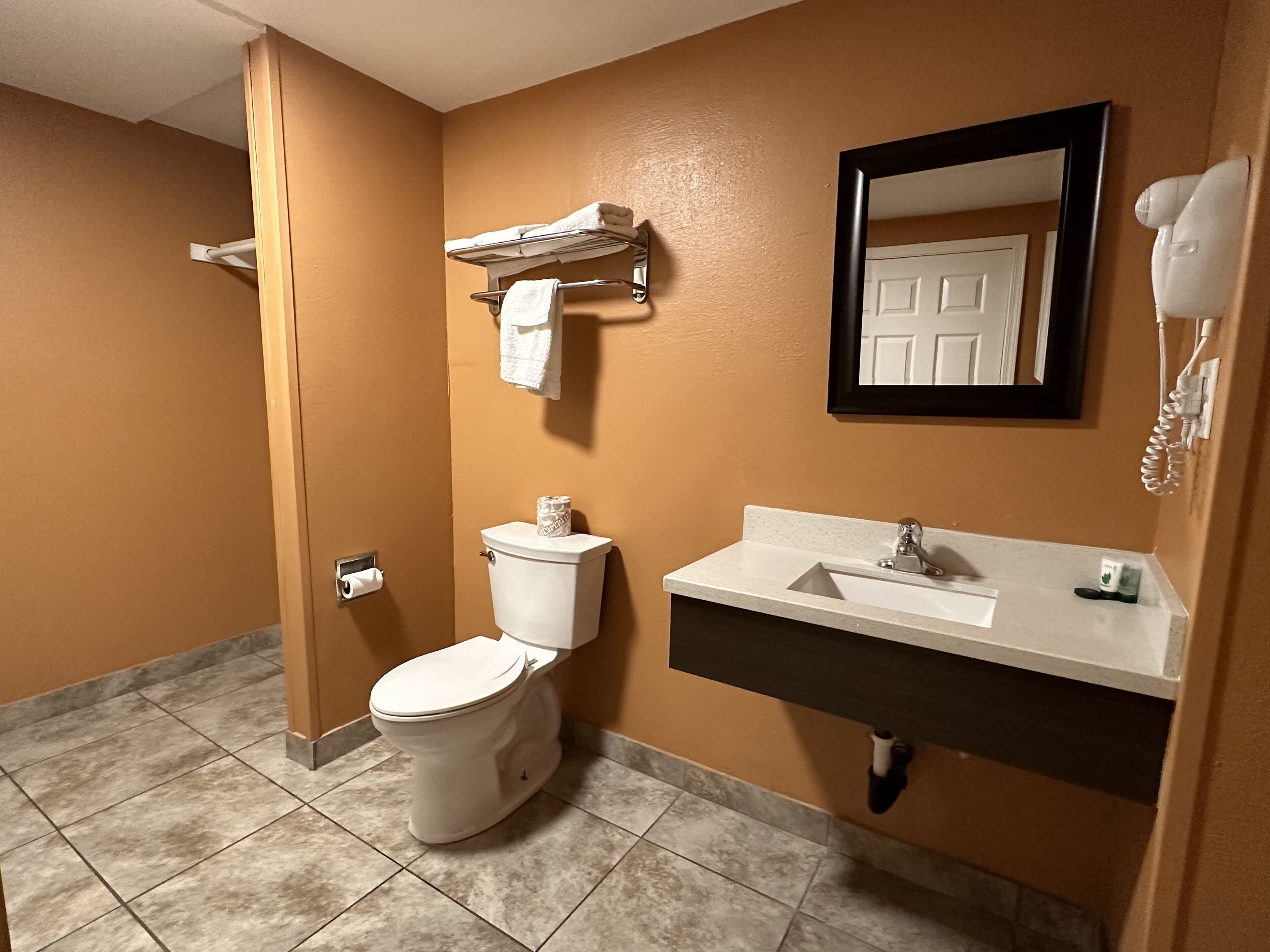 Une salle de bain équipée de toilettes, d’un lavabo, d’un porte-serviettes et d’un sèche-cheveux.