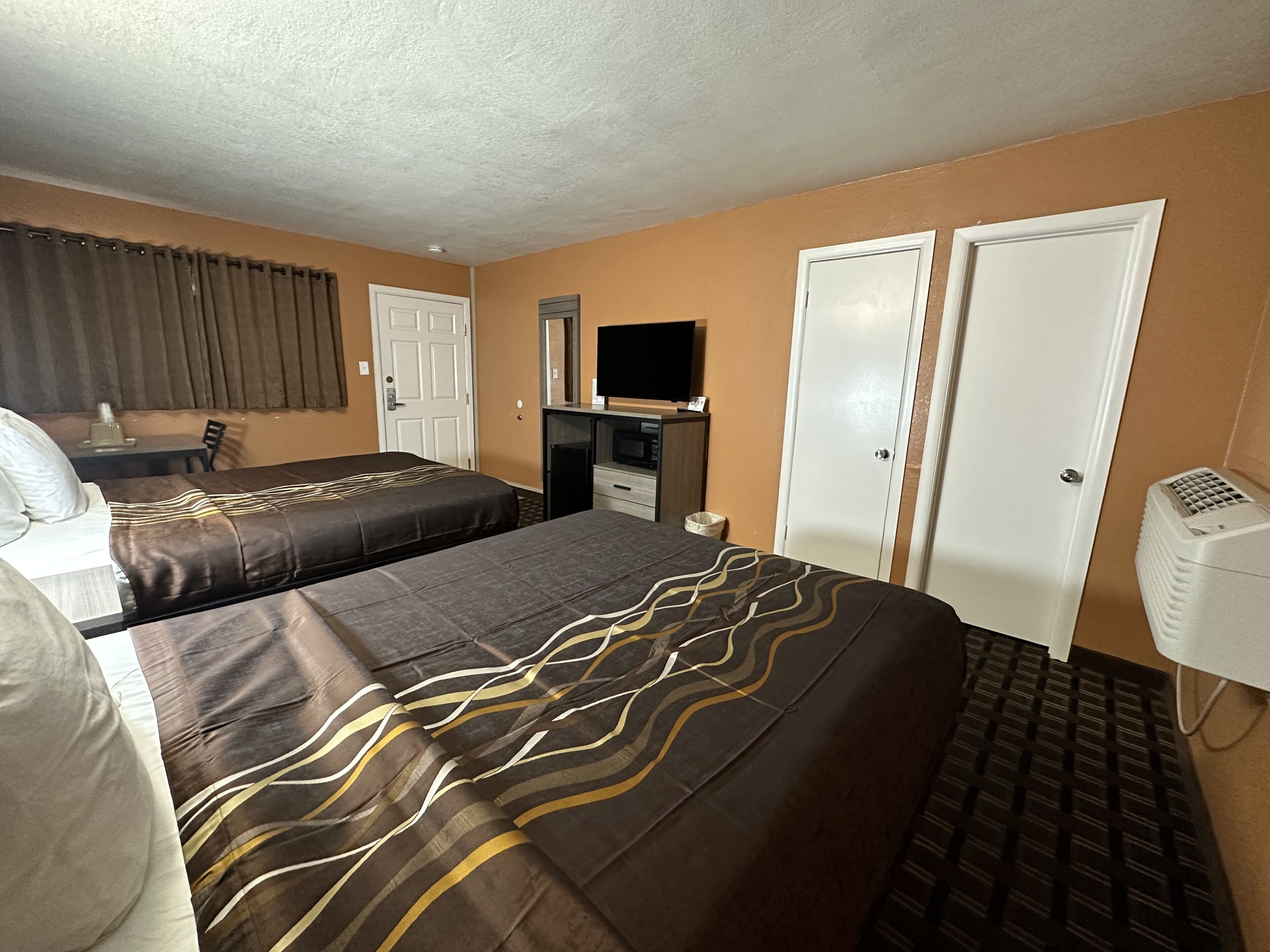 A hotel room with two beds, a desk, a TV, and a wardrobe.