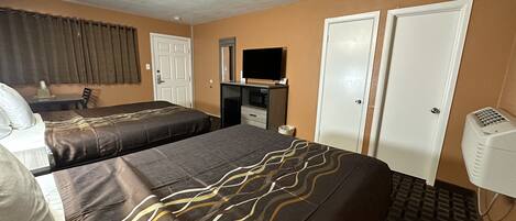 A hotel room with two beds, a desk, a TV, and a wardrobe.