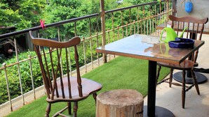A balcony with a glass table, two wooden chairs, and a railing. - Ise Guesthouse Tsumugiya - Hostel (Ise)