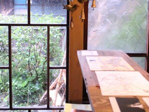 A room with a large window, a wooden table with papers, and a textured wall. - Ise Guesthouse Tsumugiya - Hostel (Ise)