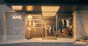 Hotel She -hotellin sisäänkäynti Kiotossa: moderni muotoilu, marmoriseinät, näkyvä jäätelömyymälän kyltti ja vaateliike.