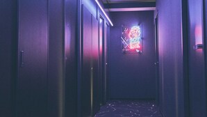 A narrow hallway with a neon sign on the wall and a patterned floor. - HOTEL SHE, KYOTO (Kyoto)