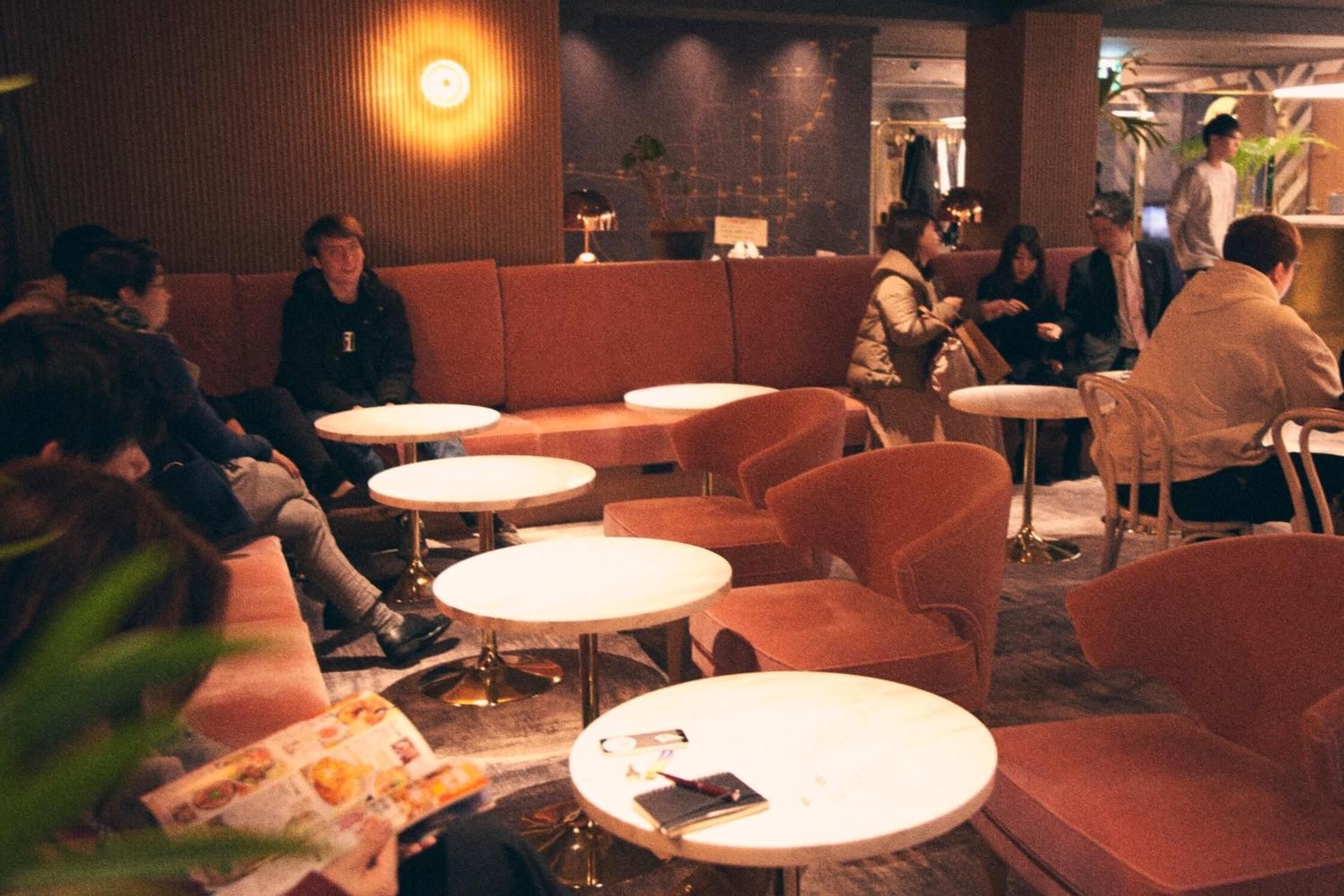 A dimly lit lounge area with round tables and cushioned seating.